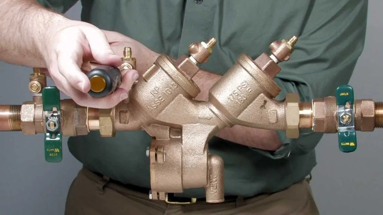Technician testing a backflow prevention assembly with a pressure gauge kit